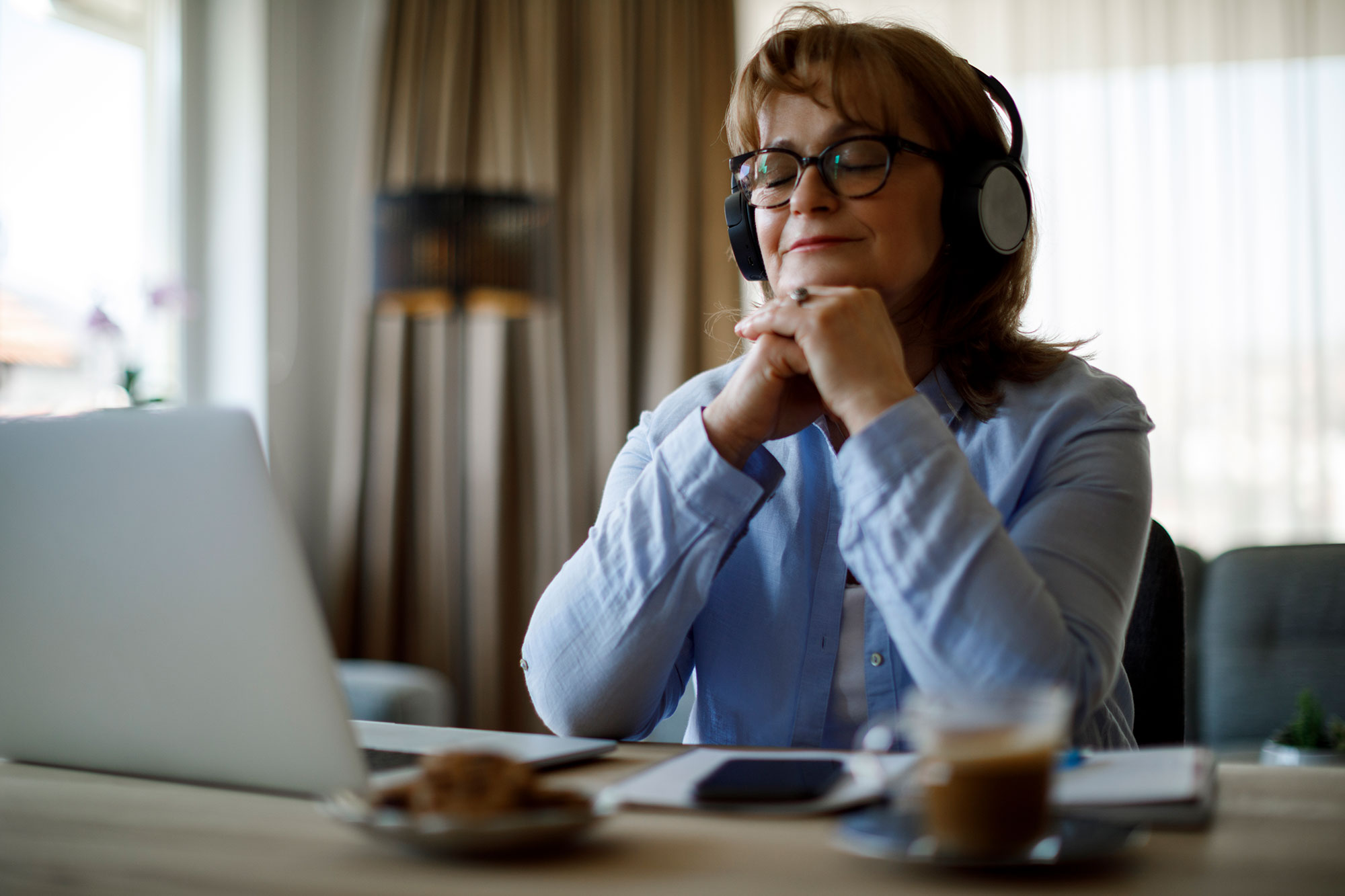 Smiling senior woman with wireless headphones enjoying music at home