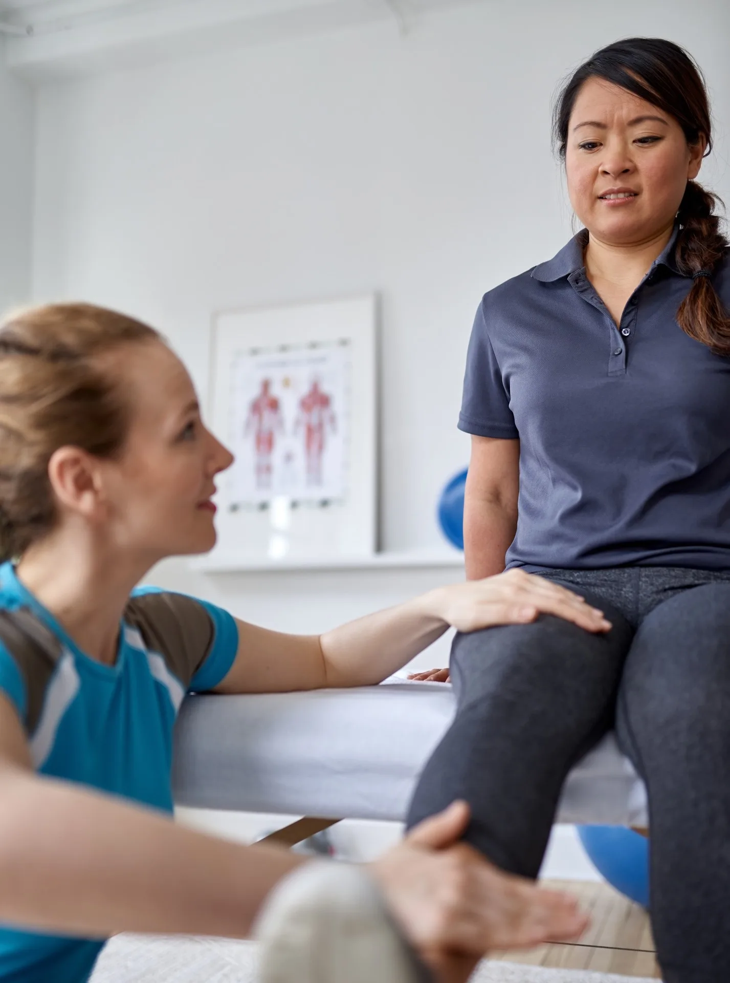 Caucasian-woman-physiotherapist-strectching-the-leg-and-knee-of-a-mid-adult-chinese-female