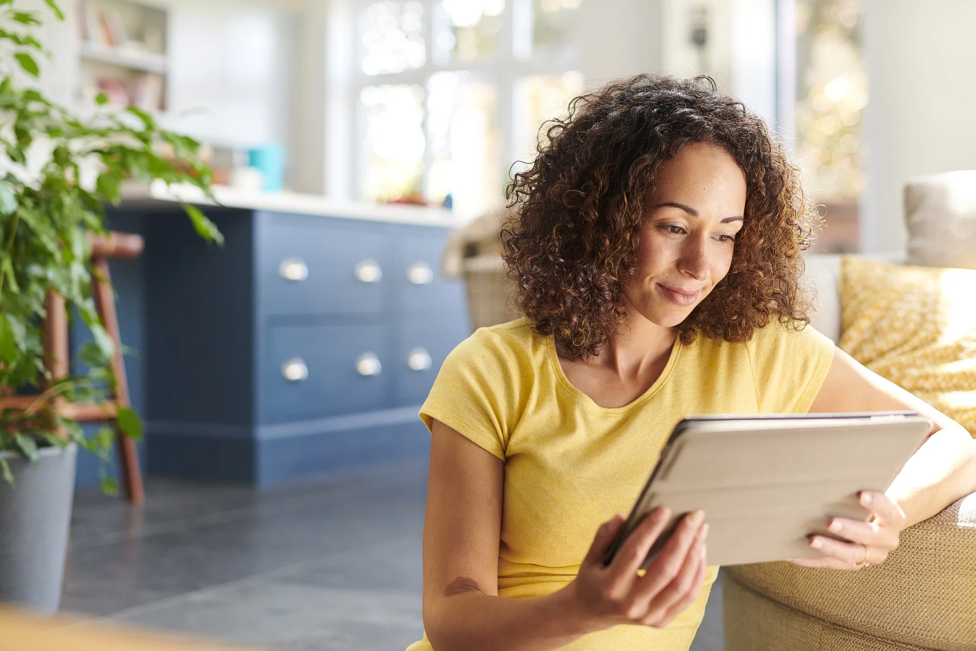 Woman in yellow t-shirt reading on an iPad